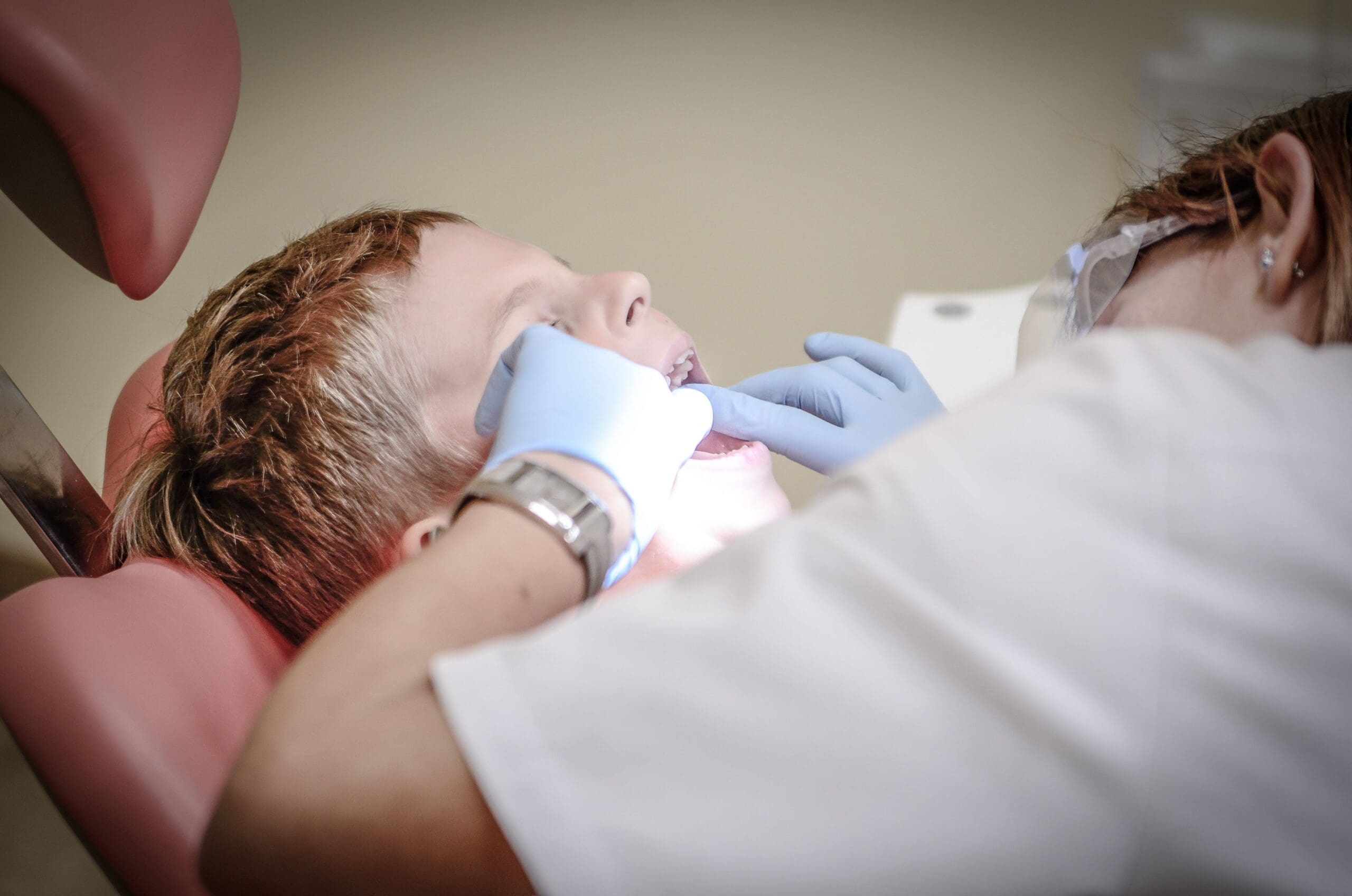 Dentist examining a child’s mouth in a dental chair.